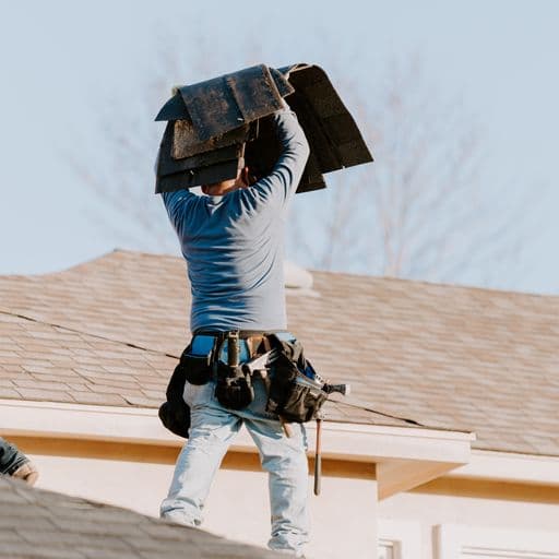 Roofer carrying shingles on a roof
