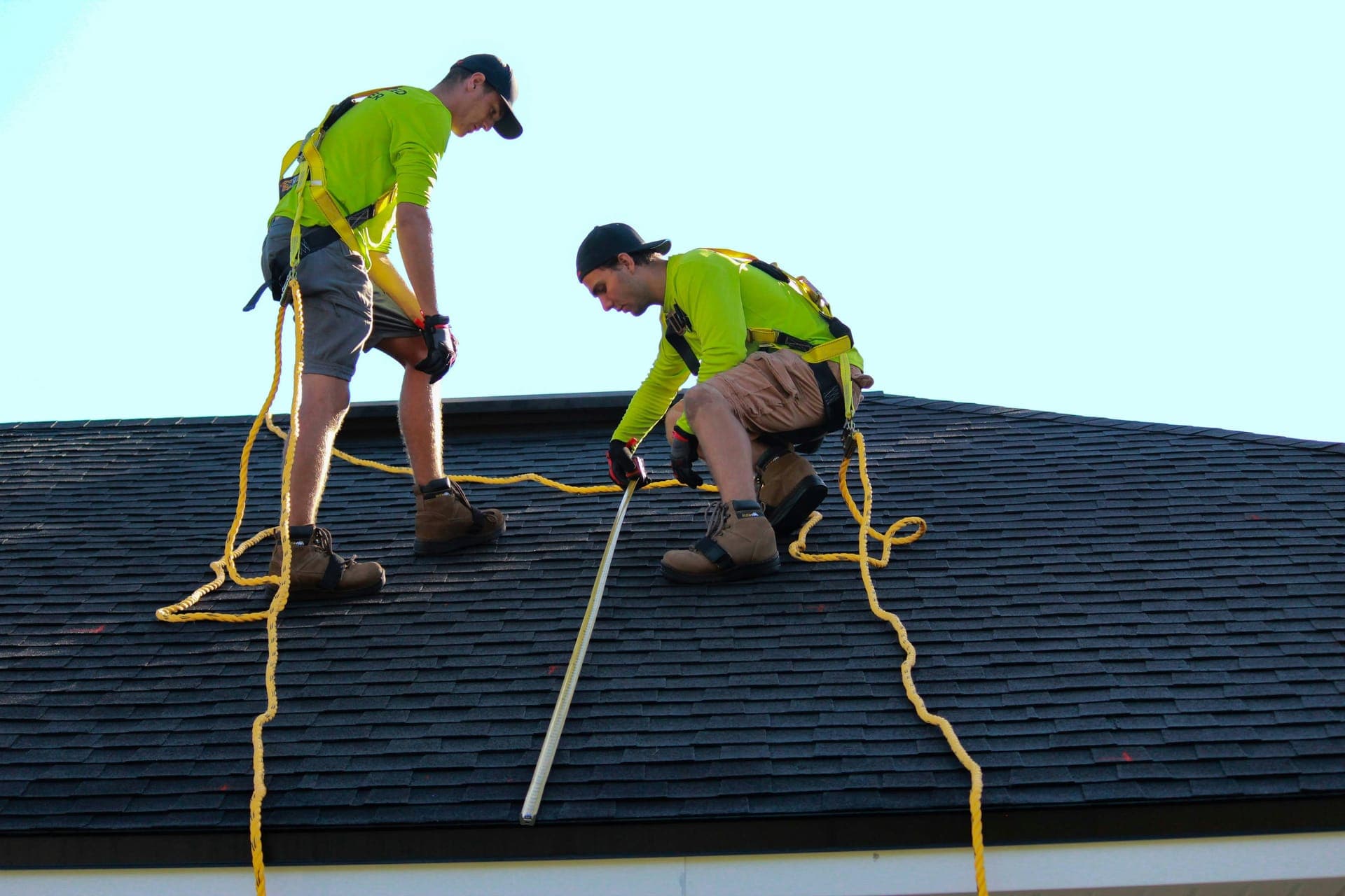 Roofers in safety harnesses working on a residential roof