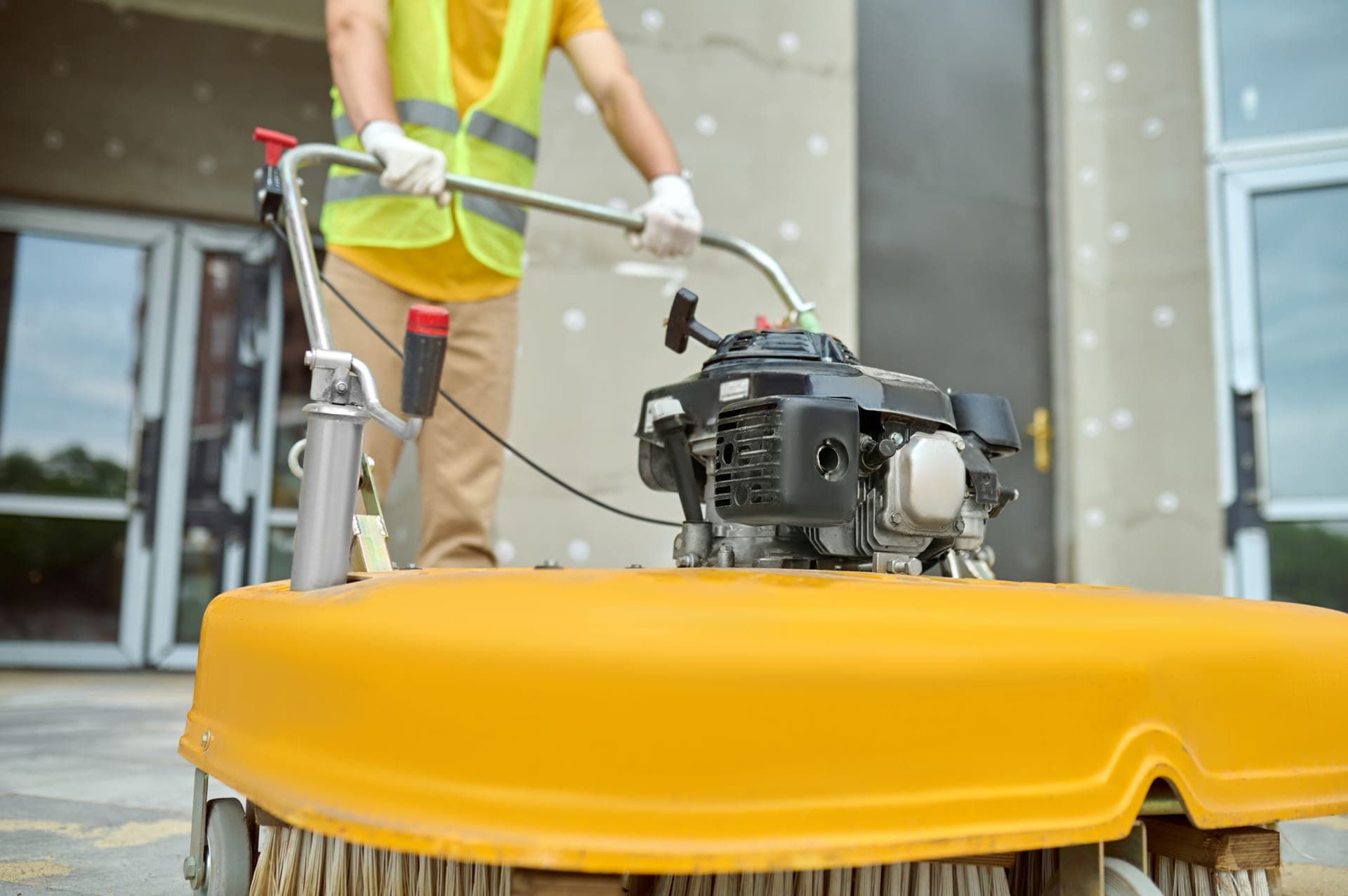 Worker using a power sweeper to clean a job site