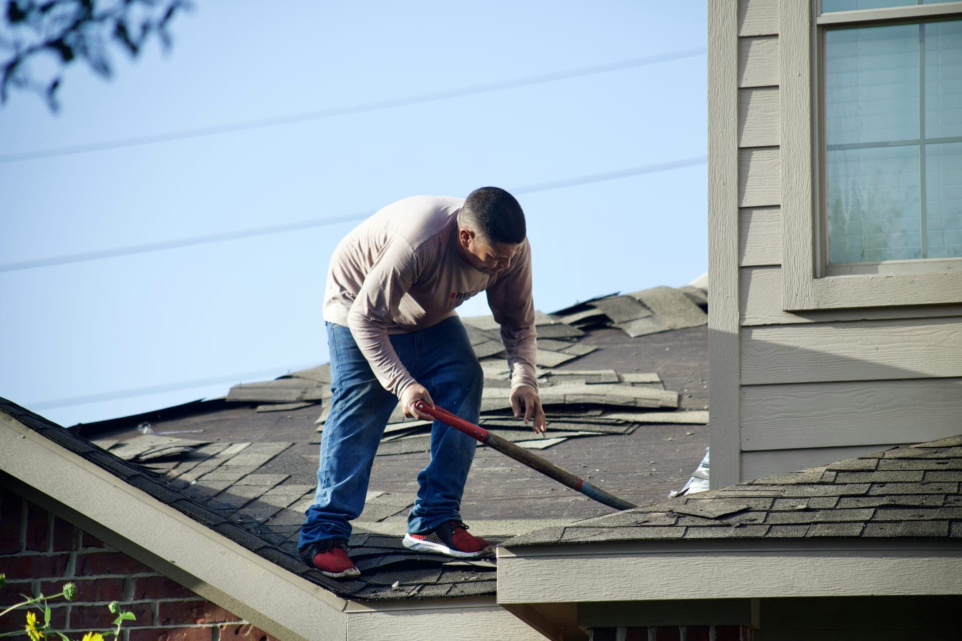 Roofer removing old shingles during a roof replacement